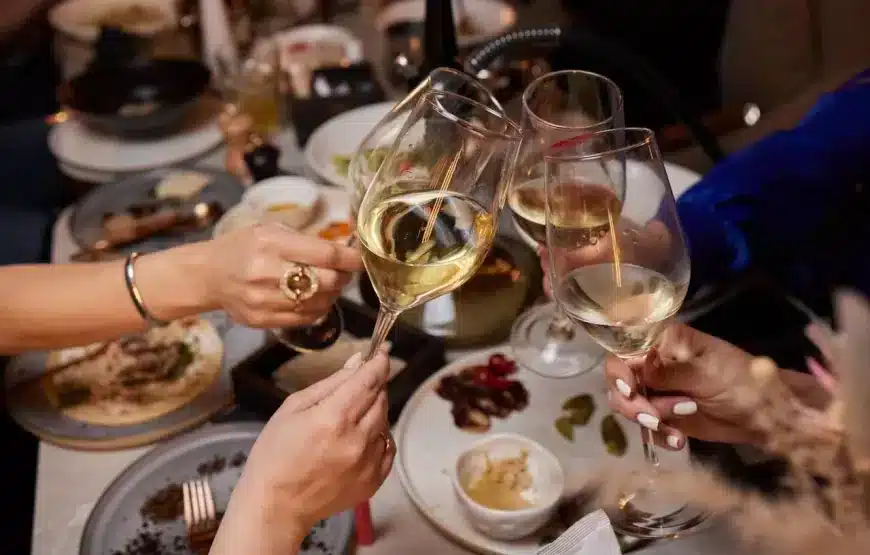 girlfriends-drinking-wine-cheering-while-sitting-bar-selective-focus-glasses-870x555